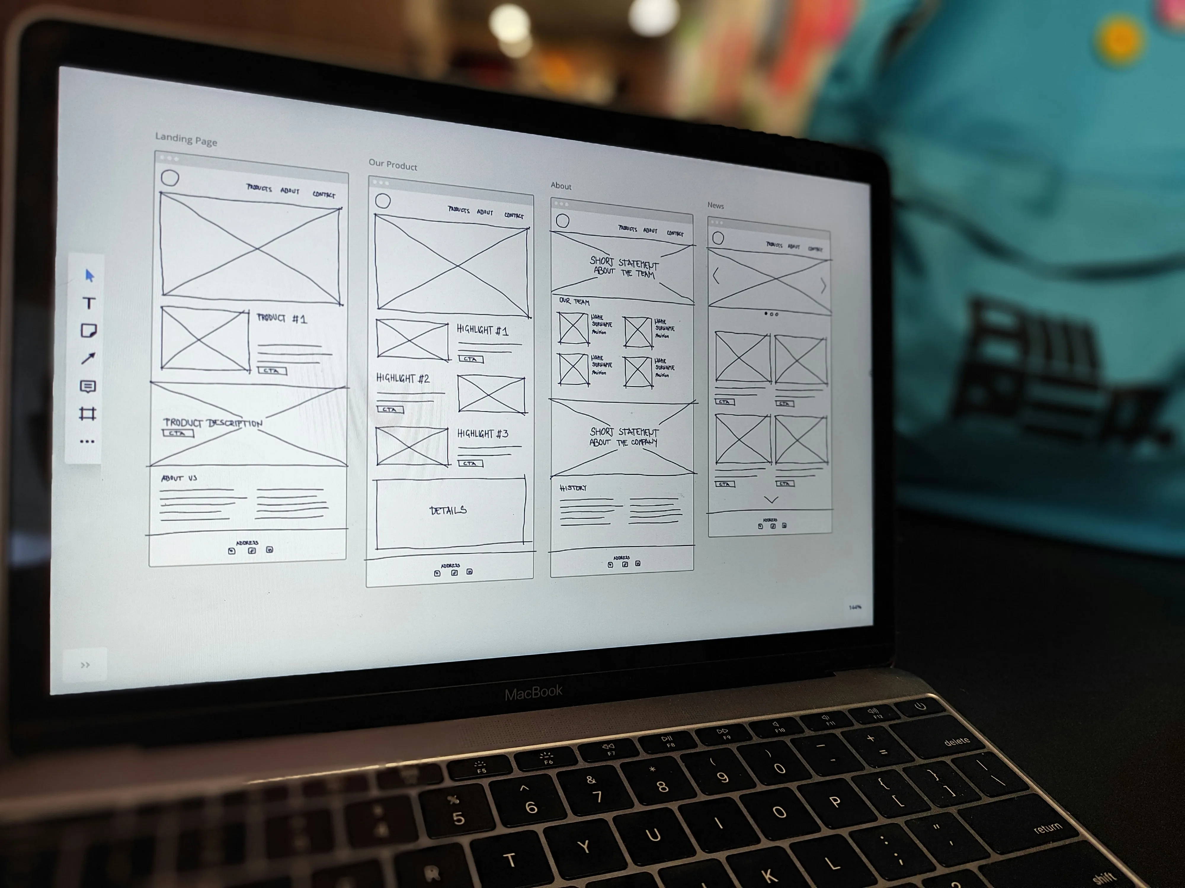 Laptop screen showing wireframe sketches of landing page, product, about, and news website layouts.