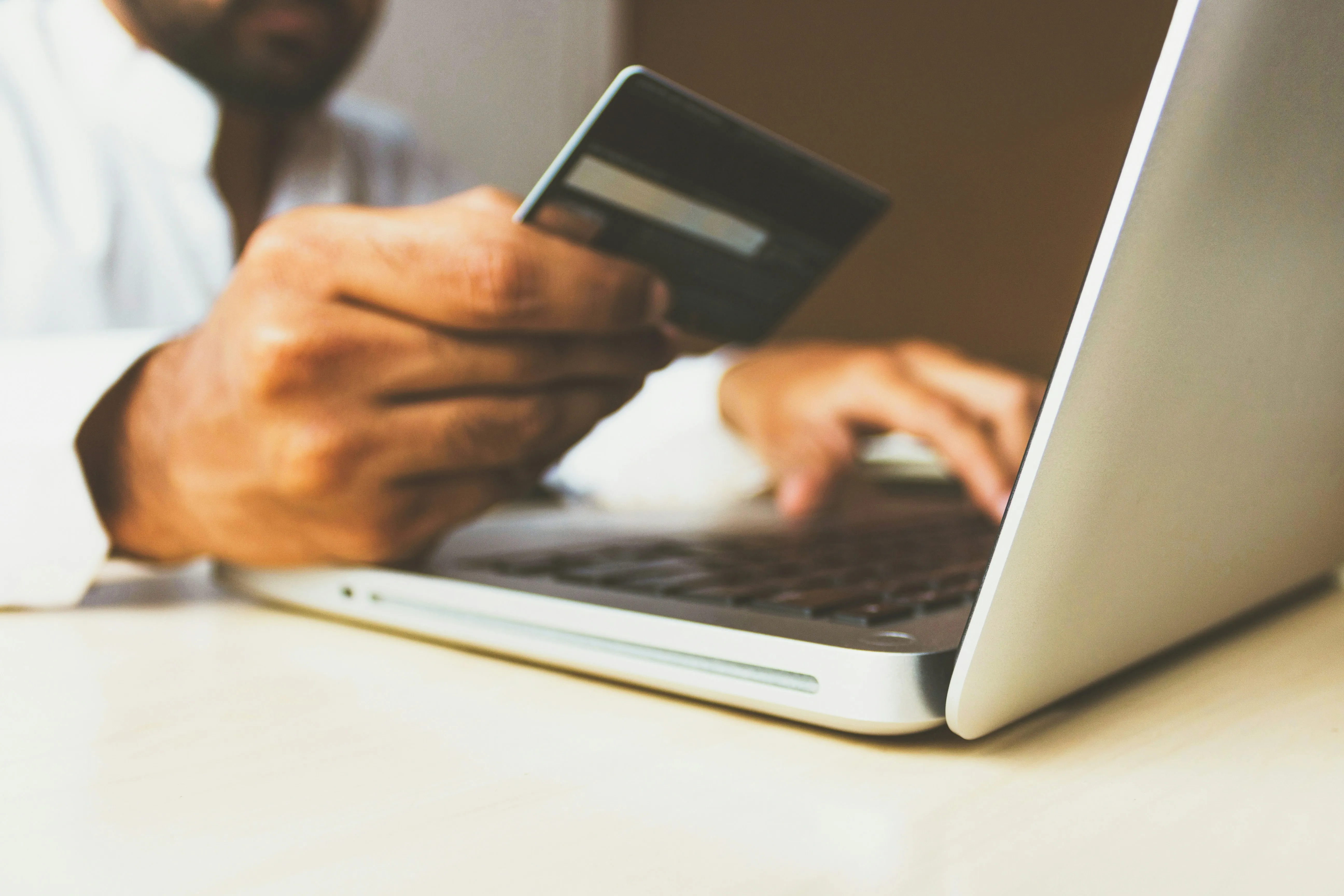 Person using laptop and holding a credit card for an online transaction.