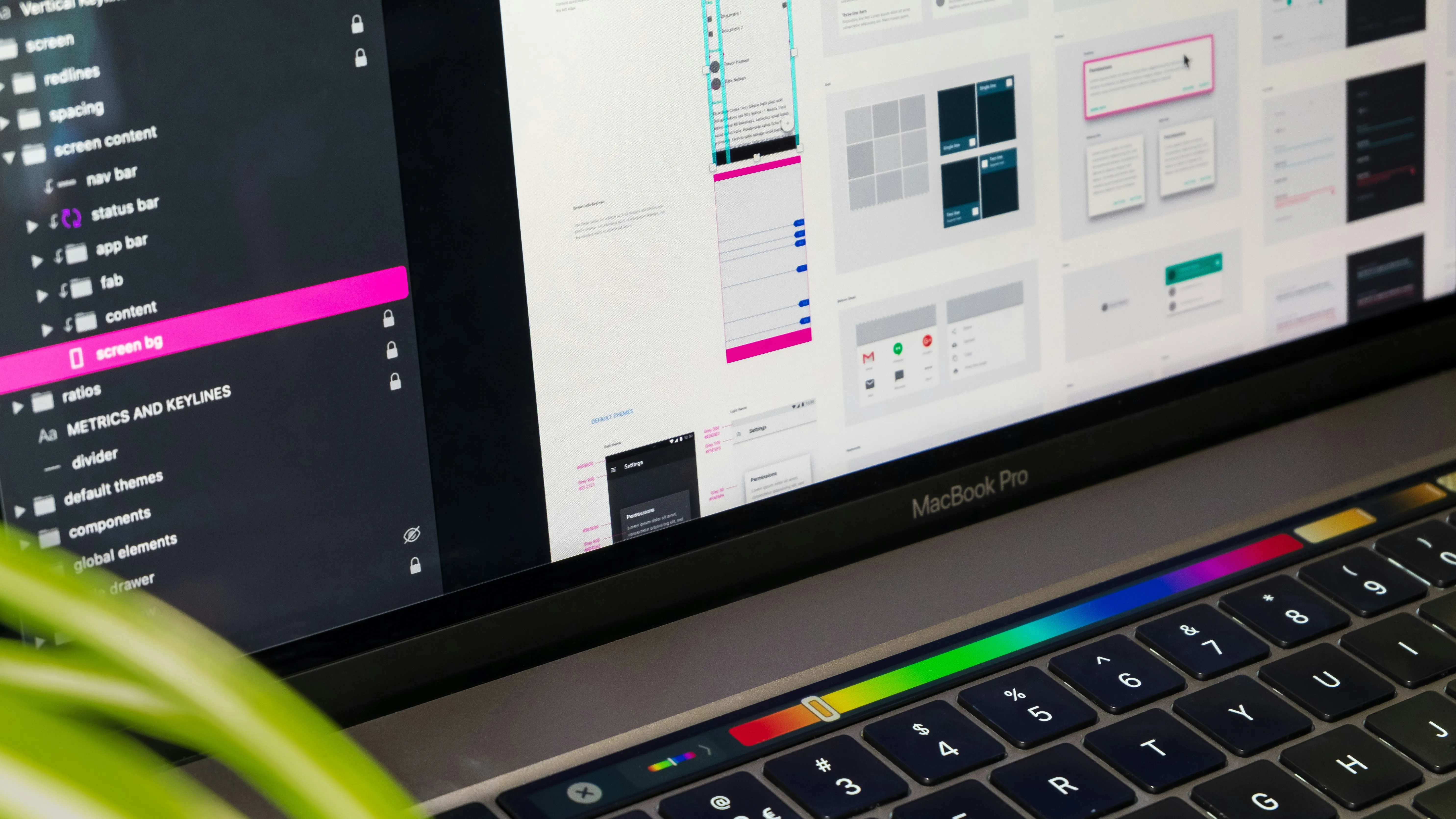 Close-up of a MacBook Pro screen showing a design app interface and a colorful touch bar.